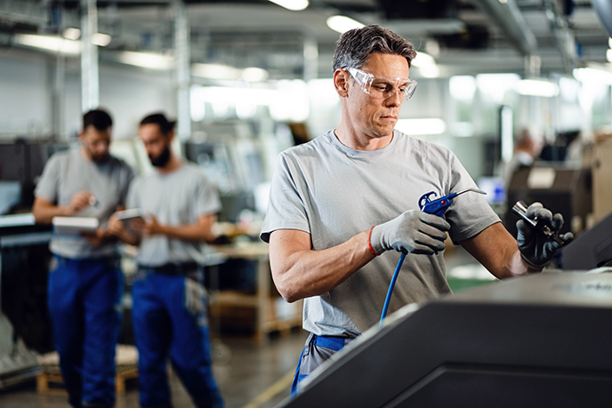 Mid adult engineer operating a CNC machine in production line in a factory